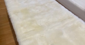 朝日が差し込む明るい寝室のツインベッドに敷かれた天然ムートンシーツ